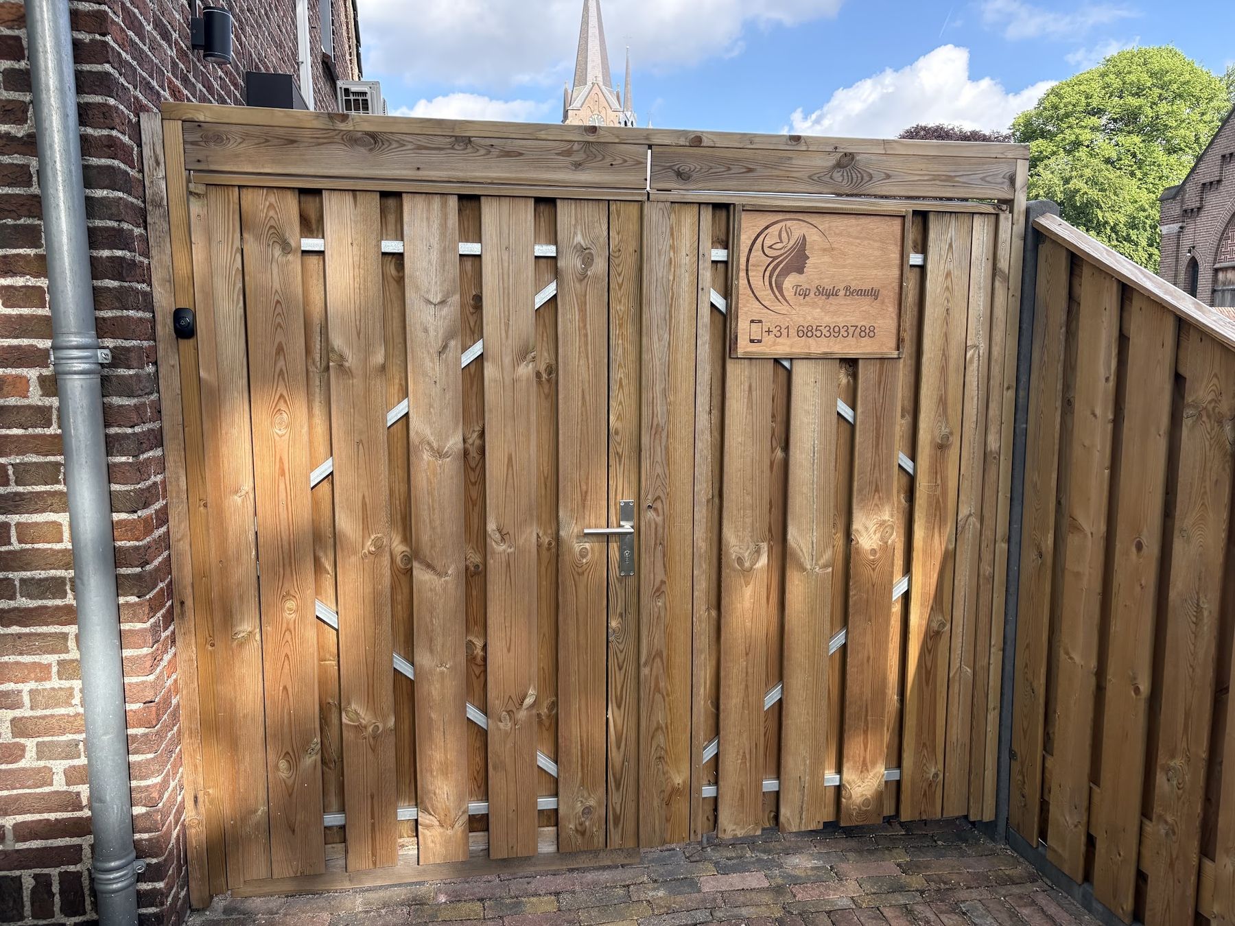 De houten poort aan de Molenstraat met het gegraveerde bord van Top Style Beauty en het telefoonnummer