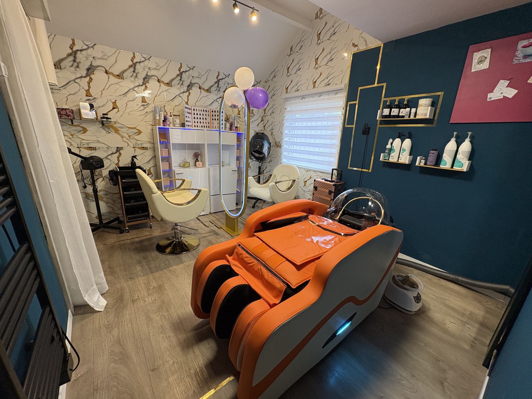 De salon van Top Style Beauty: marmeren wand met goud, twee crèmekleurige stoelen, een ovale spiegel met licht en de petrolblauwe muur